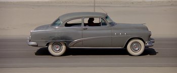 Movie still from “Zabriskie Point” (1970), directed by Michelangelo Antonioni – An old car driving down a street with a person in the driver's seat; Wide shot, Low angle