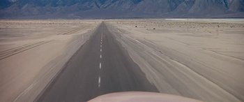 Movie still from “Zabriskie Point” (1970), directed by Michelangelo Antonioni – An empty road in the middle of a desert landscape; Extreme Wide shot, High angle