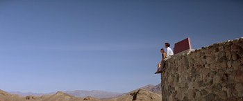 Movie still from “Zabriskie Point” (1970), directed by Michelangelo Antonioni – A man and a woman sitting on top of a rock; Extreme Wide shot, Low angle