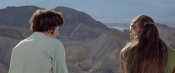 Movie still from “Zabriskie Point” (1970), directed by Michelangelo Antonioni – Two young people standing in front of some mountains; Medium shot, Over the shoulder angle