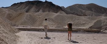 Movie still from “Zabriskie Point” (1970), directed by Michelangelo Antonioni – A man and a woman walking across a sandy beach; Extreme Wide shot, Low angle