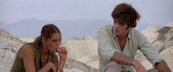 Movie still from “Zabriskie Point” (1970), directed by Michelangelo Antonioni – A man and a woman sitting next to each other on top of a hill; Medium shot, Low angle