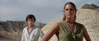 Movie still from “Zabriskie Point” (1970), directed by Michelangelo Antonioni – A man and a woman standing next to each other in the desert; Medium shot, Low angle