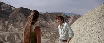 Movie still from “Zabriskie Point” (1970), directed by Michelangelo Antonioni – A man and a woman standing on top of a mountain; Medium shot, Over the shoulder angle