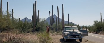 Movie still from “Zabriskie Point” (1970), directed by Michelangelo Antonioni – A man walking in front of an old car in the desert; Extreme Wide shot, Low angle