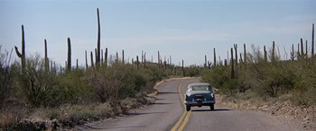 Movie still from “Zabriskie Point” (1970), directed by Michelangelo Antonioni – A car driving down a road with cactus in the background; Extreme Wide shot, Low angle