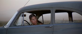 Movie still from “Zabriskie Point” (1970), directed by Michelangelo Antonioni – A woman sitting in the driver's seat of an old car; Medium shot, Over the shoulder angle