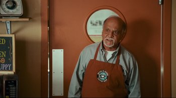 Movie still from “Zack and Miri Make a Porno” (2008), directed by Kevin Smith – An older man wearing an apron standing in front of a mirror; Medium shot, Over the shoulder angle