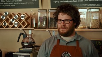 Movie still from “Zack and Miri Make a Porno” (2008), directed by Kevin Smith – A man with a beard wearing glasses and an apron in a store; Close Up shot, Over the shoulder angle