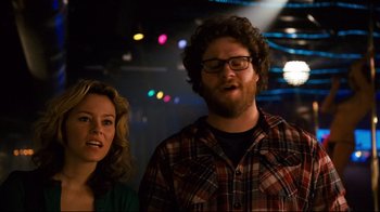 Movie still from “Zack and Miri Make a Porno” (2008), directed by Kevin Smith – A man and a woman standing next to each other in front of lights; Medium shot, Over the shoulder angle