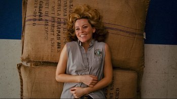 Movie still from “Zack and Miri Make a Porno” (2008), directed by Kevin Smith – A woman laying on the ground smiling for the camera; Medium shot, Overhead angle