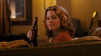Movie still from “Zack and Miri Make a Porno” (2008), directed by Kevin Smith – A woman holding up a bottle of beer in her right hand; Medium shot, Over the shoulder angle