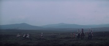 Movie still from “Zardoz” (1974), directed by John Boorman – A group of people riding horses across a field; Extreme Wide shot, High angle