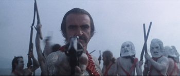 Movie still from “Zardoz” (1974), directed by John Boorman – A man holding a gun in his hand; Close Up shot, Low angle