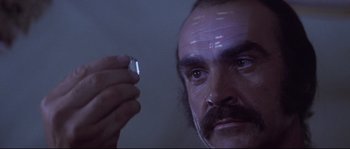 Movie still from “Zardoz” (1974), directed by John Boorman – A person holding something in his hand; Extreme Close Up shot, Low angle
