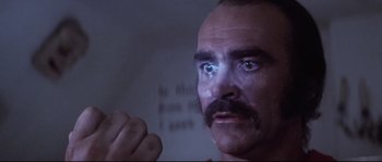 Movie still from “Zardoz” (1974), directed by John Boorman – A person with a mustache looking at the camera; Close Up shot, Low angle