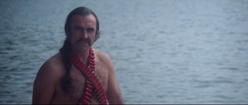 Movie still from “Zardoz” (1974), directed by John Boorman – A man with a beard is standing by the water; Medium shot, Low angle
