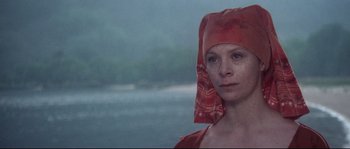 Movie still from “Zardoz” (1974), directed by John Boorman – A woman wearing a red head covering with a lake in the background; Close Up shot, High angle