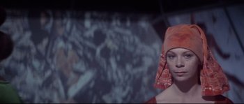 Movie still from “Zardoz” (1974), directed by John Boorman – A woman with a red head covering is looking at the camera; Close Up shot, Low angle