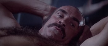 Movie still from “Zardoz” (1974), directed by John Boorman – A man with a mustache laying on a bed; Close Up shot, High angle