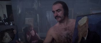 Movie still from “Zardoz” (1974), directed by John Boorman – A man with a hairy chest is looking at a woman; Medium shot, Over the shoulder angle