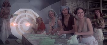 Movie still from “Zardoz” (1974), directed by John Boorman – A group of people standing around a table with food on top of it; Medium shot, Low angle
