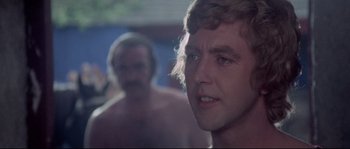 Movie still from “Zardoz” (1974), directed by John Boorman – A man standing next to another man in a room; Close Up shot, Over the shoulder angle