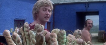 Movie still from “Zardoz” (1974), directed by John Boorman – A man standing next to a pile of bread; Close Up shot, Over the shoulder angle