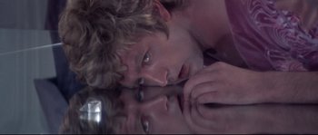 Movie still from “Zardoz” (1974), directed by John Boorman – A young man is looking at his reflection in a mirror; Close Up shot, Overhead angle