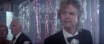 Movie still from “Zardoz” (1974), directed by John Boorman – A man in a tuxedo standing in front of a curtain; Close Up shot, Low angle