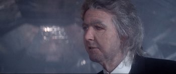 Movie still from “Zardoz” (1974), directed by John Boorman – An older man in a white shirt is looking at the camera; Close Up shot, Over the shoulder angle