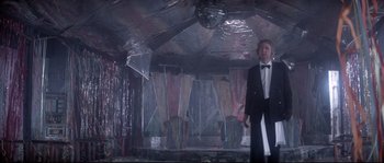 Movie still from “Zardoz” (1974), directed by John Boorman – A man in a tuxedo standing in front of a disco ball; Wide shot, Low angle