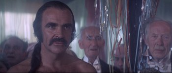 Movie still from “Zardoz” (1974), directed by John Boorman – A man with a mustache standing next to a man with a beard; Close Up shot, Over the shoulder angle