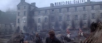 Movie still from “Zardoz” (1974), directed by John Boorman – A group of people standing in front of a building; Extreme Wide shot, Over the shoulder angle