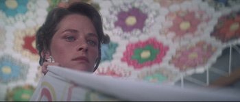 Movie still from “Zardoz” (1974), directed by John Boorman – A young woman looking at the camera while holding a quilt; Close Up shot, Low angle