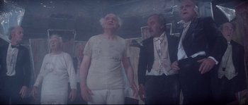 Movie still from “Zardoz” (1974), directed by John Boorman – A man in white shirt and tie next to another man in suit and tie; Medium shot, Low angle