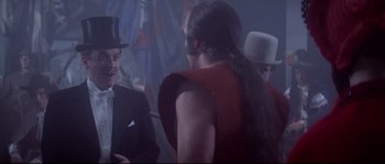 Movie still from “Zardoz” (1974), directed by John Boorman – A group of people standing in a dark room; Medium shot, Over the shoulder angle