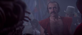 Movie still from “Zardoz” (1974), directed by John Boorman – A man with a mustache holding a gun in front of a mirror; Close Up shot, Low angle