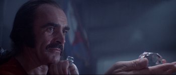 Movie still from “Zardoz” (1974), directed by John Boorman – A person holding a glass bottle; Close Up shot, Low angle