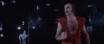 Movie still from “Zardoz” (1974), directed by John Boorman – A man with a beard holding a gun in his hand; Medium shot, Low angle