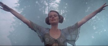 Movie still from “Zardoz” (1974), directed by John Boorman – A woman with her arms outstretched in front of a forest; Medium shot, Low angle