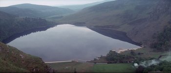 Movie still from “Zardoz” (1974), directed by John Boorman – A body of water surrounded by a lush green hillside; Extreme Wide shot, High angle