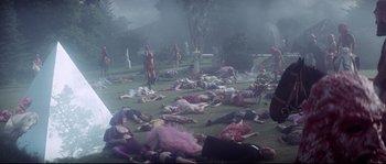 Movie still from “Zardoz” (1974), directed by John Boorman – A group of people laying on the ground in the grass; Wide shot, High angle