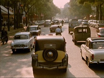 Movie still from “Zazie dans le Métro” (1960), directed by Louis Malle – An image of cars driving down the street in the middle of the day; Extreme Wide shot, High angle