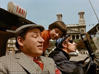 Movie still from “Zazie dans le Métro” (1960), directed by Louis Malle – A group of people sitting on a scooter in the street; Medium shot, High angle