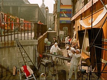 Movie still from “Zazie dans le Métro” (1960), directed by Louis Malle – A group of people standing around in an alleyway; Wide shot, High angle