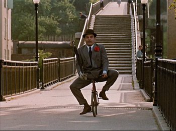Movie still from “Zazie dans le Métro” (1960), directed by Louis Malle – A man riding a bike down a street with stairs in the background; Wide shot, High angle