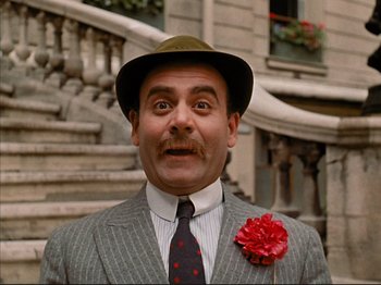 Movie still from “Zazie dans le Métro” (1960), directed by Louis Malle – A man in a suit and a hat with a flower in his lapel; Close Up shot, Low angle