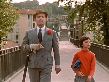 Movie still from “Zazie dans le Métro” (1960), directed by Louis Malle – A man and a boy walking across a bridge; Medium shot, Low angle