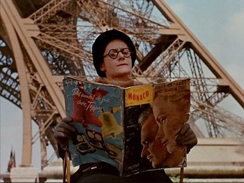 Movie still from “Zazie dans le Métro” (1960), directed by Louis Malle – A person sitting in a chair reading a magazine; Medium shot, Low angle